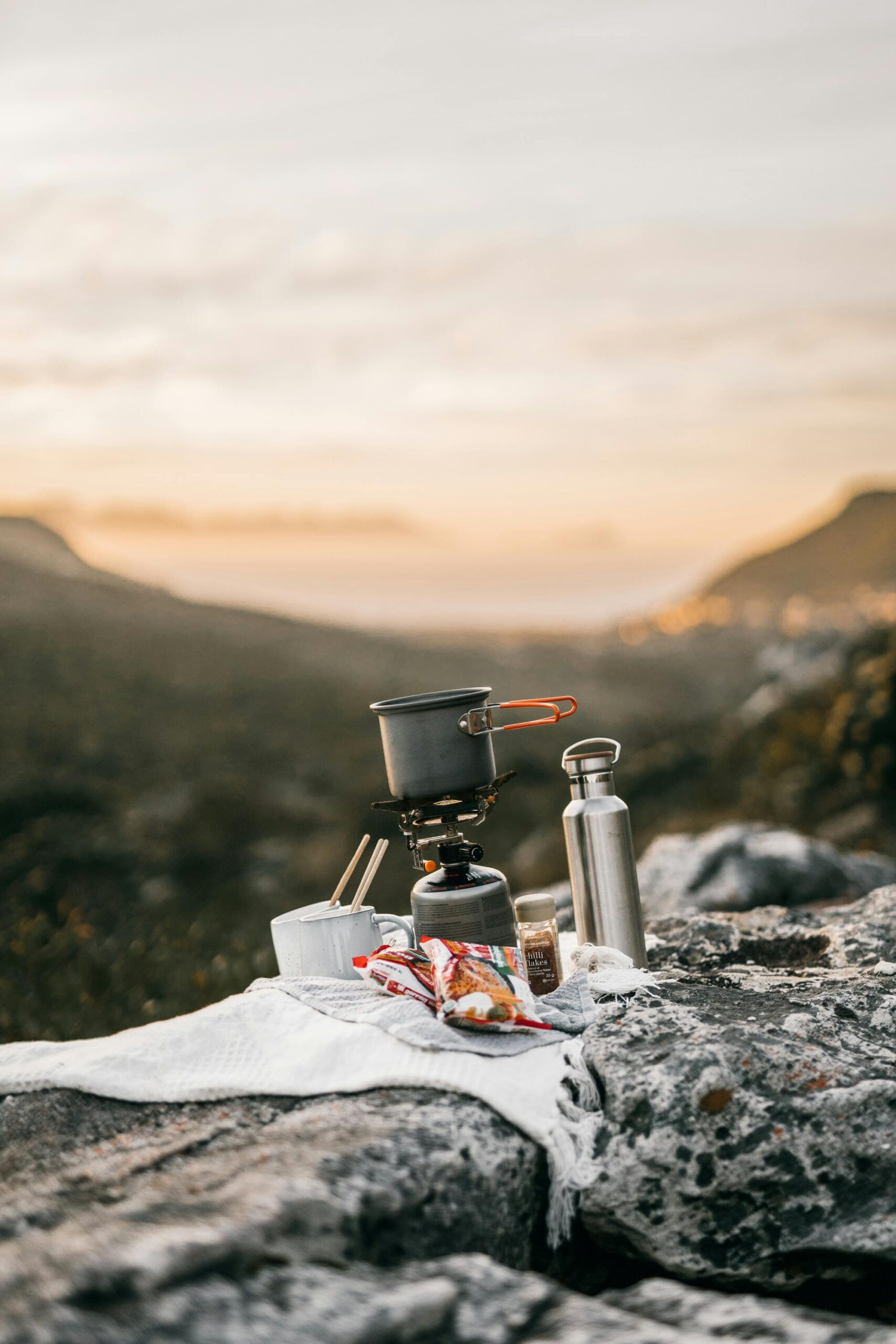 Enjoy a serene mountain morning with a hot breakfast cooked on a portable gas burner at sunrise.